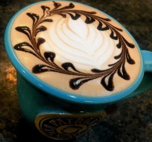 Blue coffee mug filled with foam and chocolate drizzle.