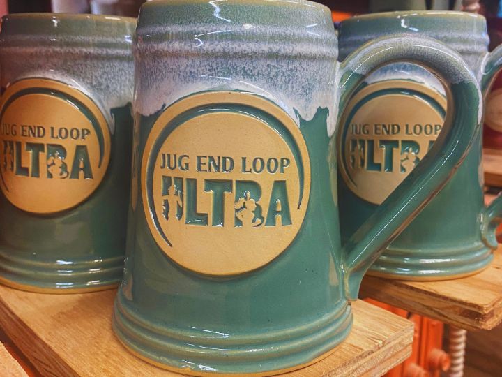 Green and white ceramic beer stein with logo medallion that reads "Jug End Loop Ultra". 