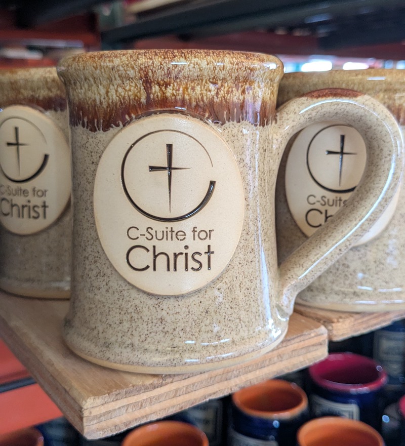 tan pottery mug with a church logo in the center