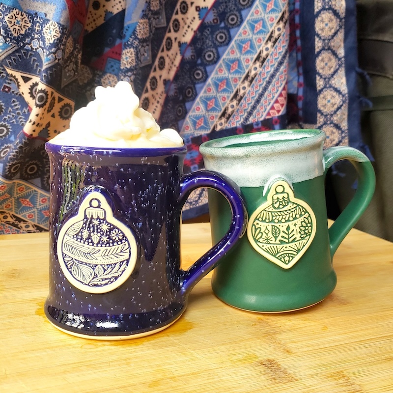 two holiday themed coffee mugs on a table